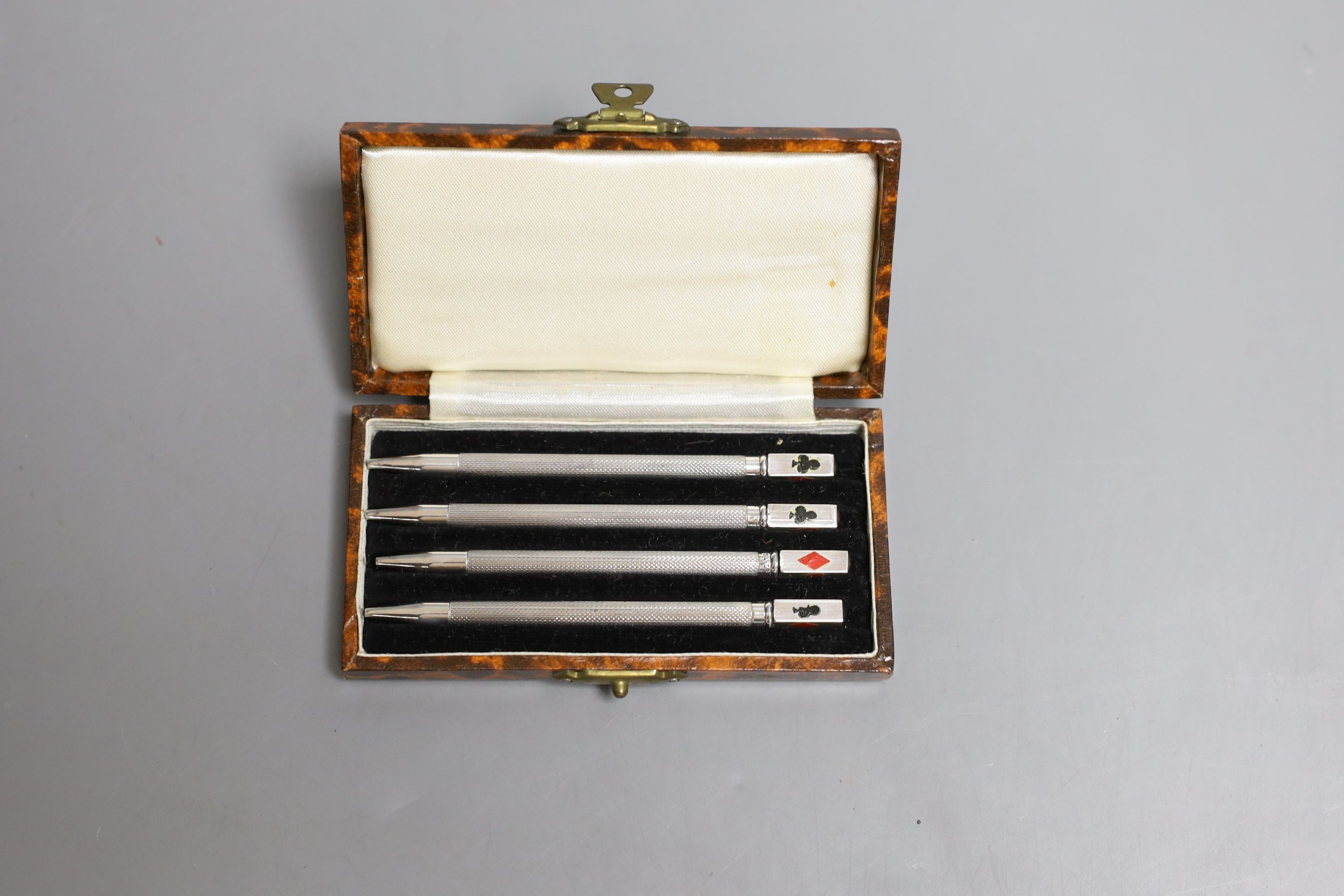 A cased set of four engine turned sterling and enamel bridge pencils, 9cm.